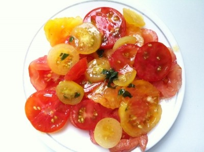 Personal size tomato plate on a saucer drizzled with basil/oregano infused extra virgin olive oil and aged balsamic vinegar.